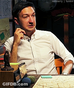 Man In White Shirt Sitting At Table With Map And Monkey Statue GIF