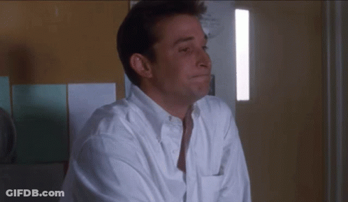 Man In White Shirt Sitting In Front Of Wall GIF