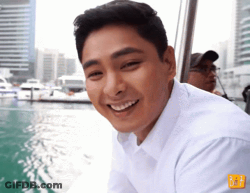 Man In White Shirt Smiling In Front Of B & T Sign GIF
