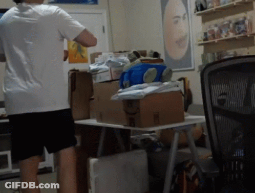 Man In White Shirt Standing At Table With Boxes GIF