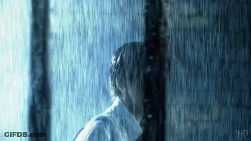Man In White Shirt Standing Behind Pole In Rain GIF