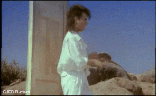 Man In White Shirt Standing By Wooden Door GIF