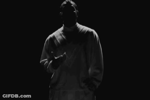 Man In White Shirt Standing In Darkness GIF