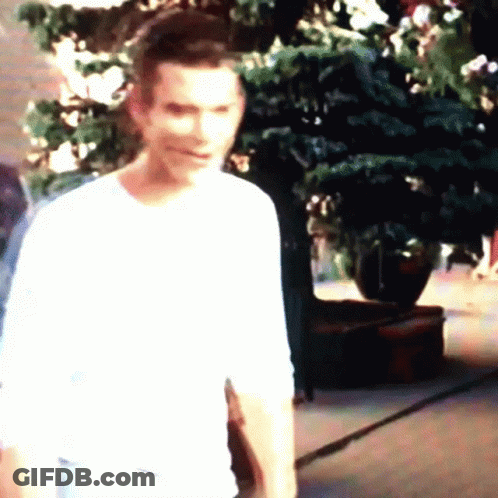 Man In White Shirt Standing In Front Of Christmas Tree GIF