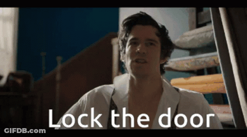 Man In White Shirt Standing In Front Of Door Saying Lock The Door GIF