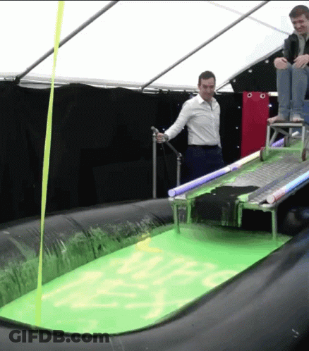 Man In White Shirt Standing In Green Liquid With Yellow Ribbon GIF