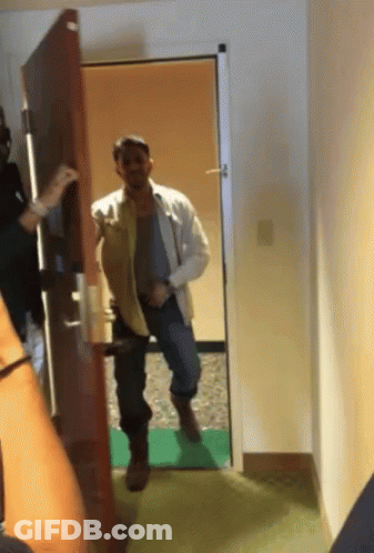 Man In White Shirt Standing In Hallway GIF
