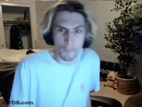 Man In White Shirt Standing In Room With Plant And Chair GIF