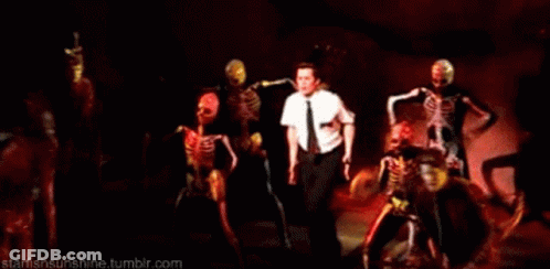 Man In White Shirt Surrounded By Dancing Skeletons GIF
