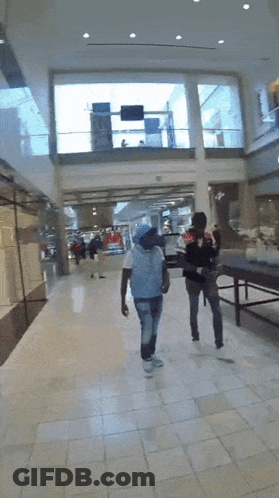 Man In White Shirt Walking Down Hallway GIF