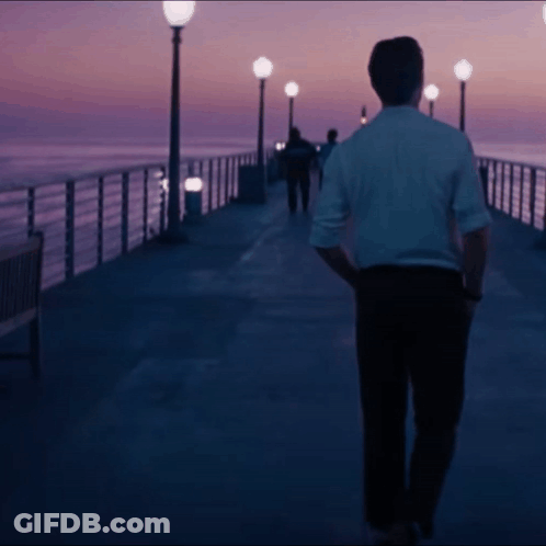 Man In White Shirt Walking Down Pier At Night GIF