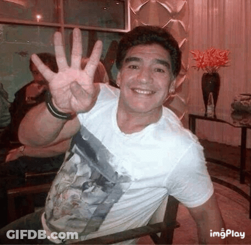 Man In White Shirt Waving While Sitting GIF