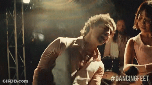 Man In White Shirt With Bottles Sitting On Couch Hands Folded GIF