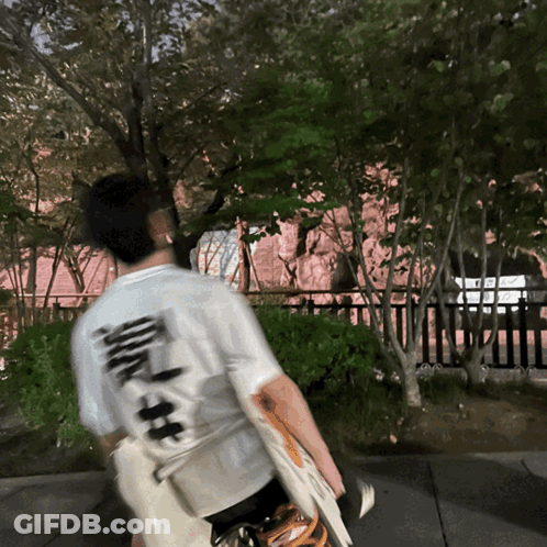 Man In White Shirt With Chinese Writing Walking Down Sidewalk GIF