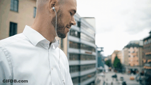 Man In White Shirt With Earbuds Looking Down GIF