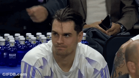 Man In White Shirt With Purple Stripes Sitting At Table Full Of Water Bottles GIF