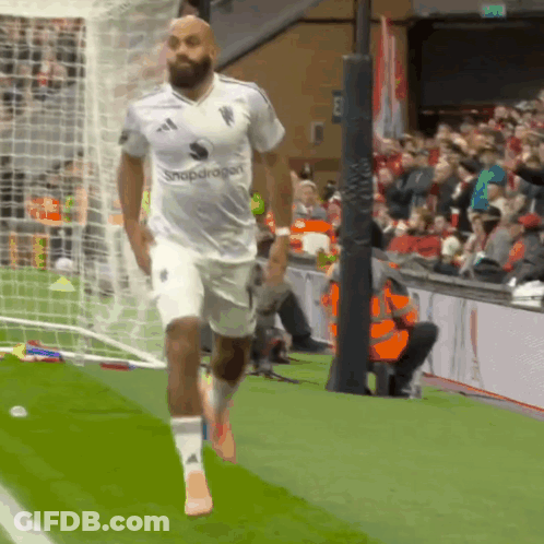 Man In White Snapdragon Shirt Running Soccer Field GIF