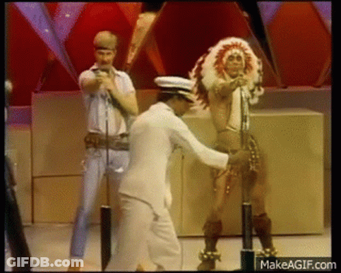 Man In White Suit Dancing With Woman In Native American Costume GIF