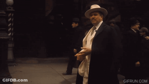 Man In White Suit Holding Orange Cigar Co. Sign GIF