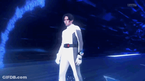 Man In White Suit In Dark Room With Blue Background GIF