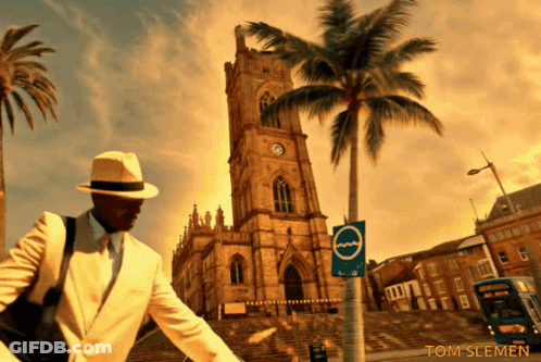 Man In White Suit In Front Of Clock Tower With Palm Tree GIF