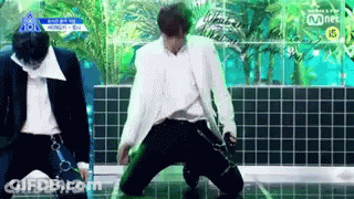 Man In White Suit Kneeling On Stage, Another Standing GIF
