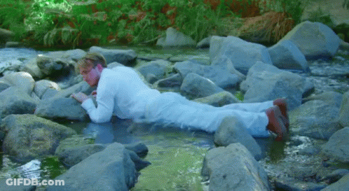 Man In White Suit Lying On Rocks GIF