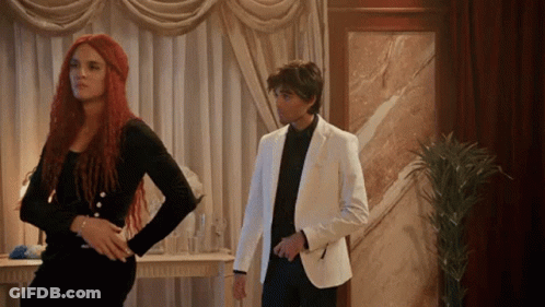 Man In White Suit Next To Woman With Red Hair GIF