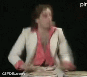 Man In White Suit Playing Drums In Dark Room GIF