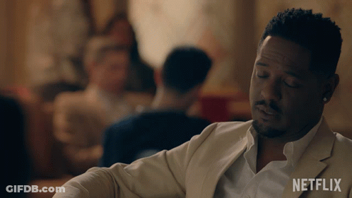 Man In White Suit Sitting In Front Of Netflix Sign GIF