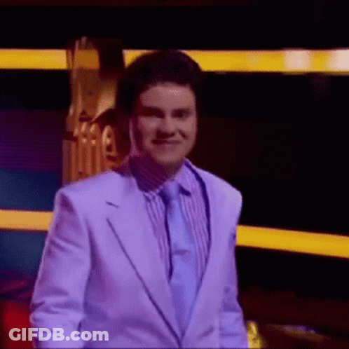 Man In White Suit Smiling In Front Of Stage GIF