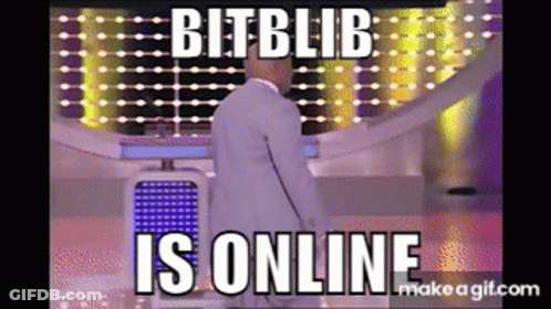 Man In White Suit Standing In Front Of Bit Blib Is Online Screen GIF