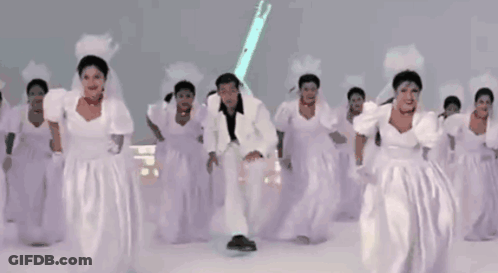 Man In White Suit Surrounded By Bridesmaids GIF