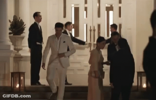 Man In White Suit Walking Down Stairs With Woman In Red Dress GIF