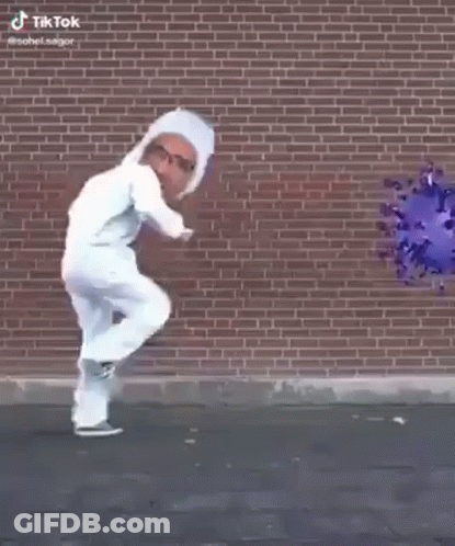 Man In White Suit Walking In Front Of Brick Wall With Virus Picture GIF