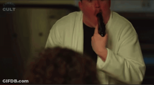 Man In White Sweater Holding Black Object In Mouth Saying Comes Cult GIF
