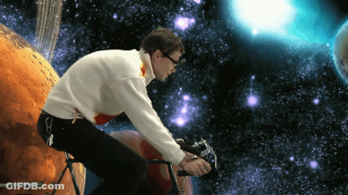 Man In White Sweater Riding Bike In Front Of Planet GIF