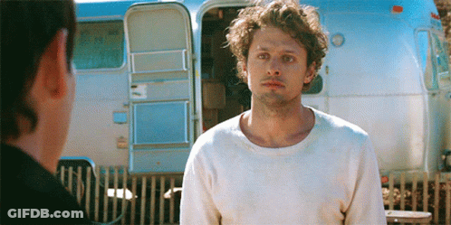 Man In White Sweater Standing In Front Of Trailer GIF