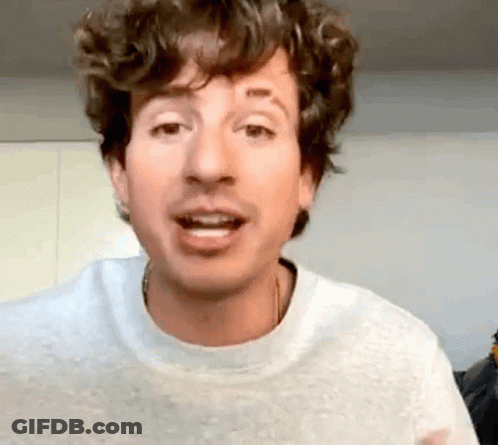 Man In White Sweater With Curly Hair And Tattoo Making Funny Face GIF