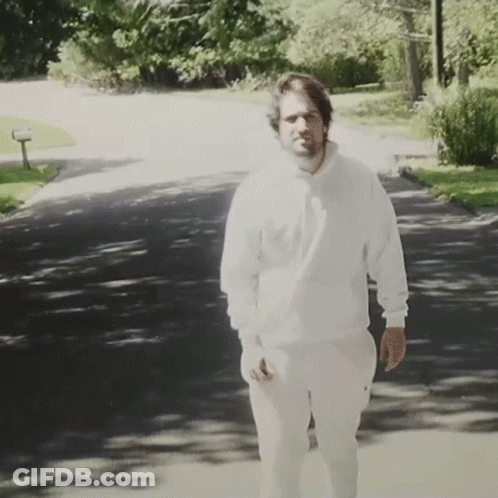 Man In White Sweatshirt And Pants Walking Down Road GIF