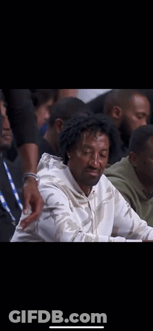Man In White Sweatshirt Sitting In Crowd GIF