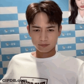 Man In White T-Shirt Black Logo Staring Camera GIF
