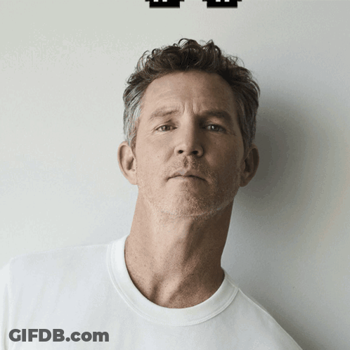 Man In White T-Shirt In Front Of Wall GIF