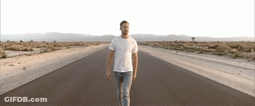 Man In White T-Shirt Walking Desert Road GIF