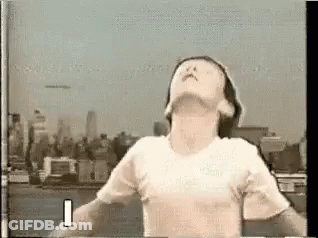 Man In White T-Shirt With Arms Outstretched City Skyline GIF