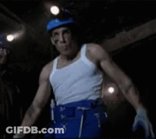 Man In White Tank Top And Blue Pants Standing In Dark Room GIF