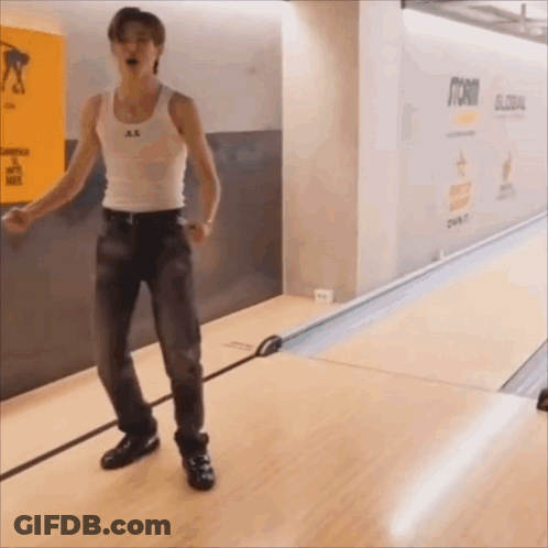 Man In White Tank Top And Jeans At Bowling Alley GIF