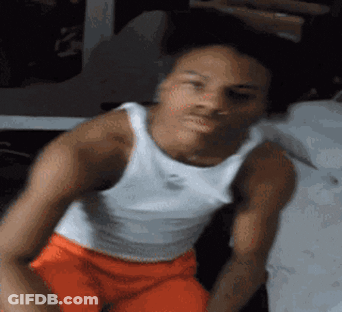 Man In White Tank Top And Orange Shorts Sitting On Chair GIF