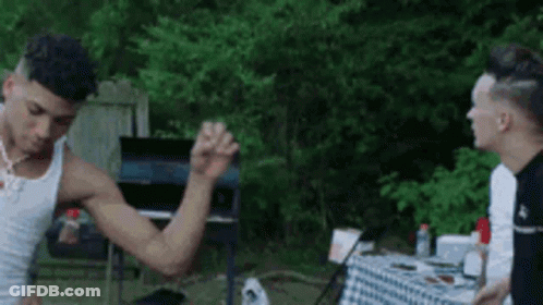 Man In White Tank Top Flexing Muscles At Table GIF