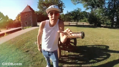 Man In White Tank Top Holding Cannon GIF